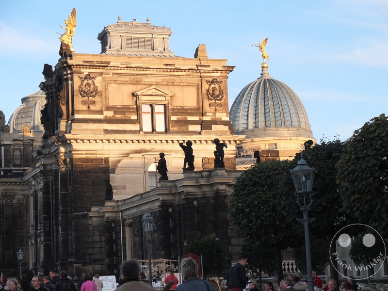 Deutschland - Dresden - Kunstakademie - Zitronenpresse - Historisches Gebäude mit Kuppeln und goldenen Statuen, Menschen und Bäume im Sonnenuntergang.