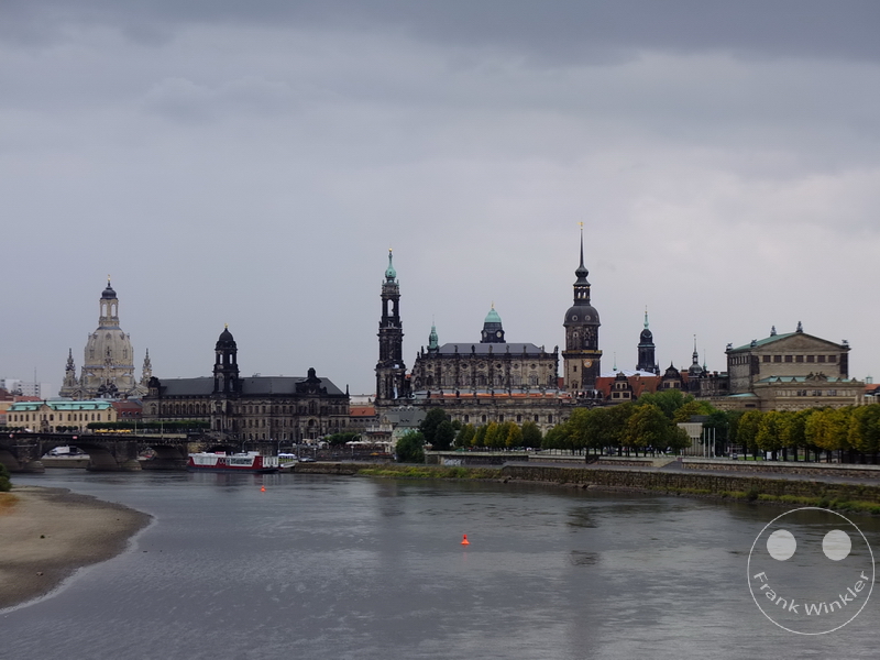 Deutschland - Dresden - Canaletto-Blick - Stadtpanorama mit Fluss, historischen Gebäuden, Türmen, Kuppelkirche und bewölktem Himmel.