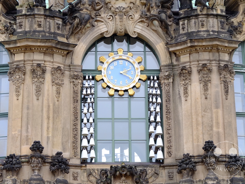 Deutschland Dresden - Zwinger- Historisches Gebäude mit goldumrahmter Uhr und weißen Glocken, dekoriert mit Ornamenten.