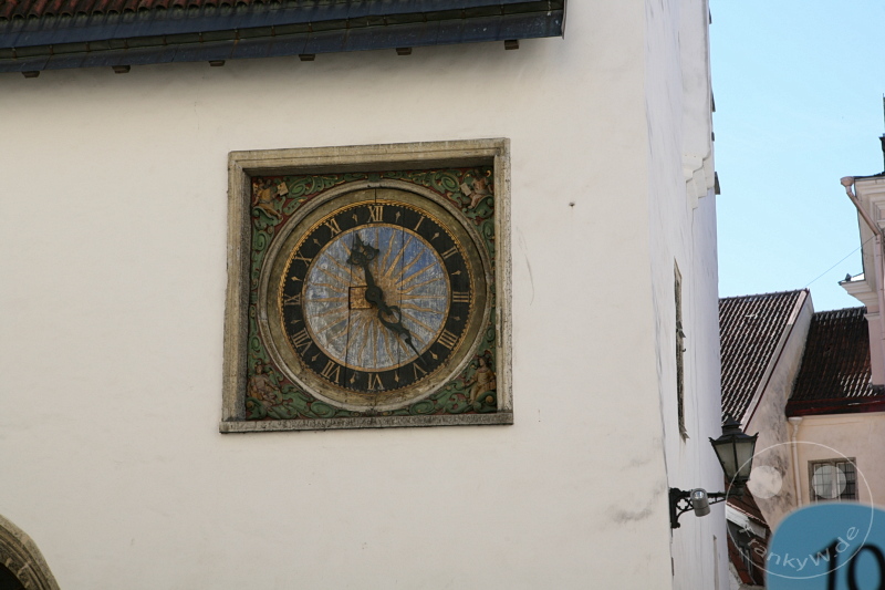 Estland - Tallinn - Antike Turmuhr mit römischen Ziffern und Abnutzung auf reich verziertem Hintergrund.