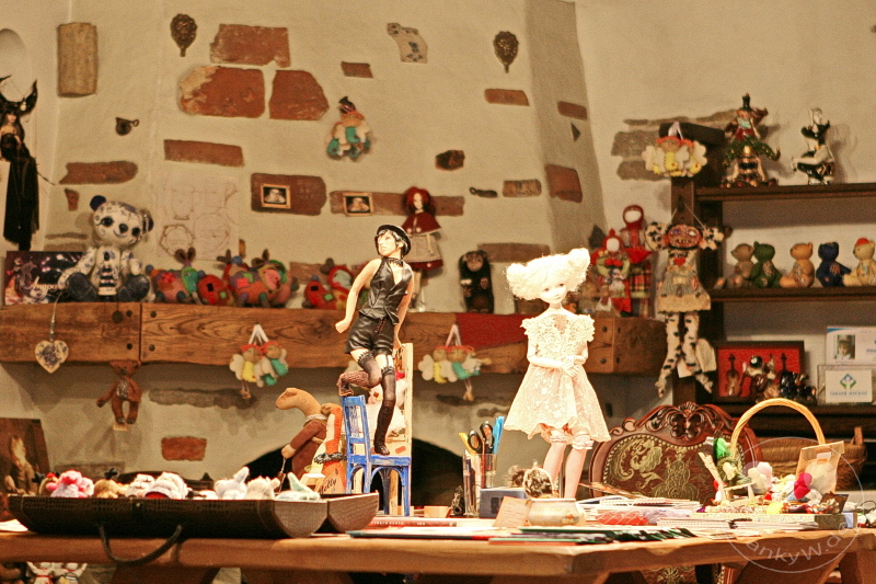 Estland - Tallinn - Raum mit dekorativen Puppen, Stofftieren, bunten Figuren, handgemachten Arbeiten, rustikaler Wand.