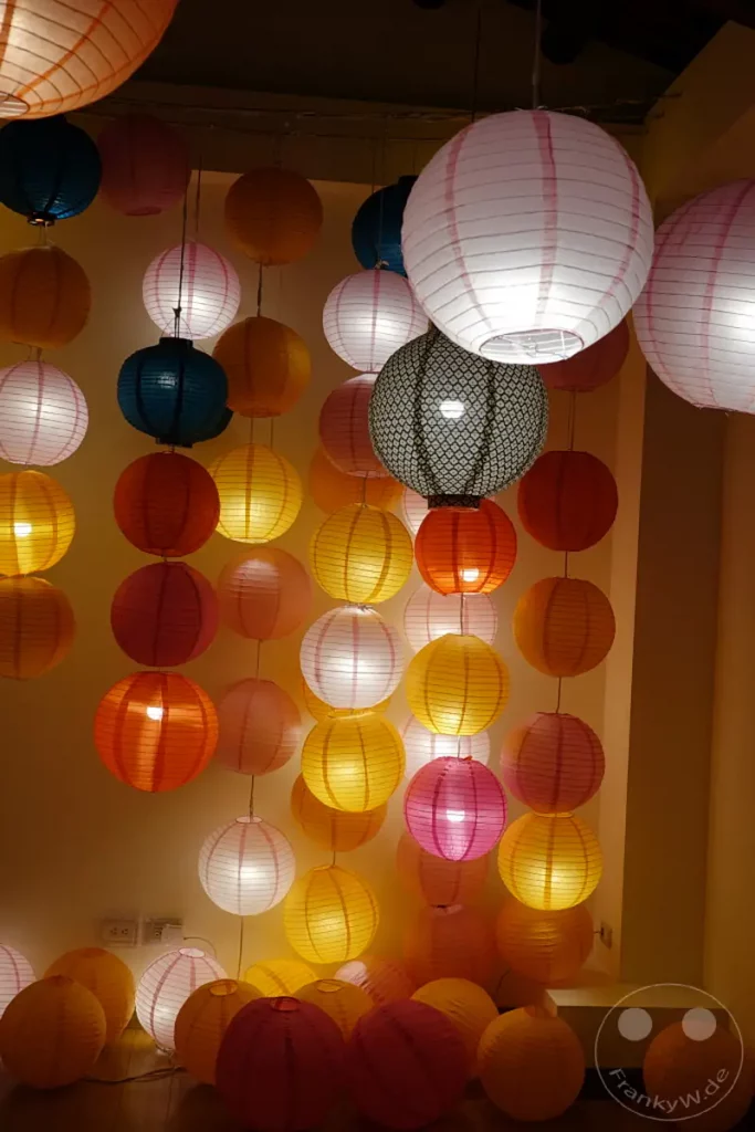 Eine Fülle von bunten Papierlaternen hängt in verschiedenen Größen und Farben und erzeugt eine festliche und einladende Atmosphäre in Taipeh, Taiwan. Das sanfte Licht der Laternen beleuchtet die Szene und taucht sie in warme Töne, was eine traditionelle und lebendige Stimmung erzeugt. Diese Dekoration ist typisch für Festivitäten und Märkte entlang der Dihua Street.