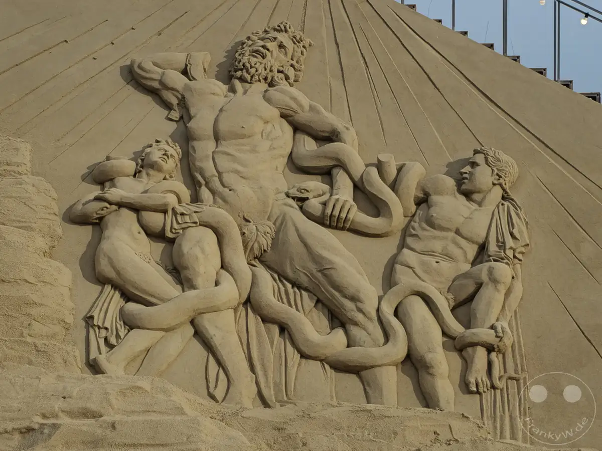 Am Haeundae Beach in Busan, Südkorea, thront eine beeindruckende Sandskulptur, die eine mythologische Szene darstellt. Drei Figuren, umgeben von Schlangen, kämpfen in einem dramatischen Relief. Die feinen Details und die kraftvollen Posen erzeugen eine dynamische und epische Atmosphäre.
