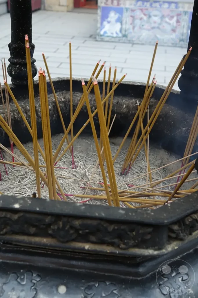 In Taiwan, genauer gesagt in Taipeh auf der Dihua Street, glühen Weihrauchstäbchen in einem großen Räuchergefäß. Feiner Rauch steigt von den brennenden Spitzen auf und vermittelt eine Atmosphäre der Besinnung und Spiritualität. Die Asche der verbrannten Stäbchen sammelt sich im Gefäß und zeugt von zahlreichen Ritualen.