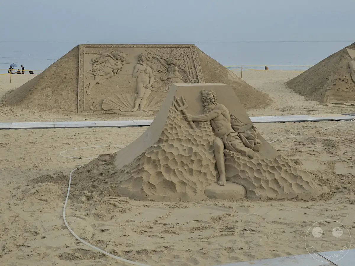Auf dem Haeundae Beach in Busan, Südkorea, sind beeindruckende Sandskulpturen am Ufer aufgestellt. Die Kunstwerke, darunter Darstellungen mythologischer Figuren und Szenen, schaffen eine faszinierende Kulisse am Meer. Die ruhige See und der weite Sandstrand unterstreichen die künstlerische Atmosphäre dieser temporären Installation.
