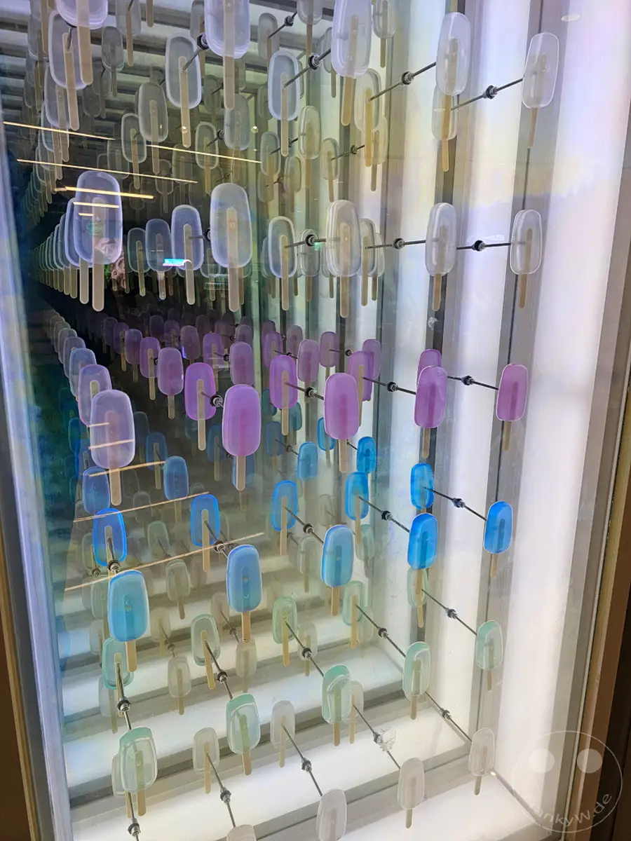 Eine endlose Reihe von bunten Eis-Skulpturen erstreckt sich in einem Spiegelkabinett in der Starfield Coex Mall in Seoul, Südkorea. Die leuchtenden Farben von Lila, Blau und Türkis schaffen eine verspielte und faszinierende Atmosphäre. Diese Installation lädt zum Staunen und Erkunden der unendlichen Reflexionen ein.