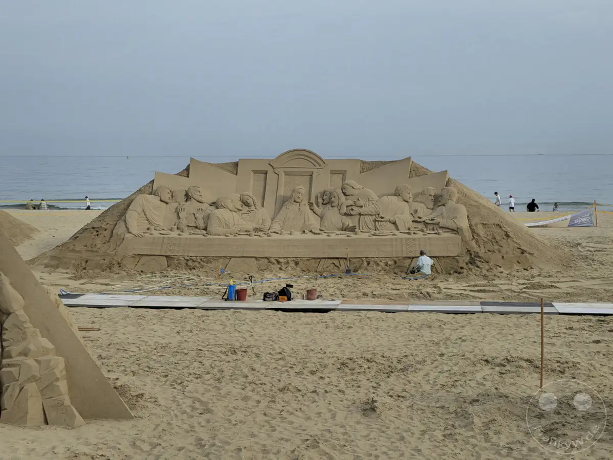 Eine beeindruckende Sandskulptur der "Letzten Abendmahl"-Szene schmückt den Haeundae Beach in Busan, Südkorea. Die detailreiche Darstellung von Jesus und seinen Jüngern im Sand zeugt von der Kunstfertigkeit der Bildhauer. Die ruhige Meereskulisse und der weite Sandstrand schaffen eine friedliche Atmosphäre für dieses temporäre Meisterwerk.