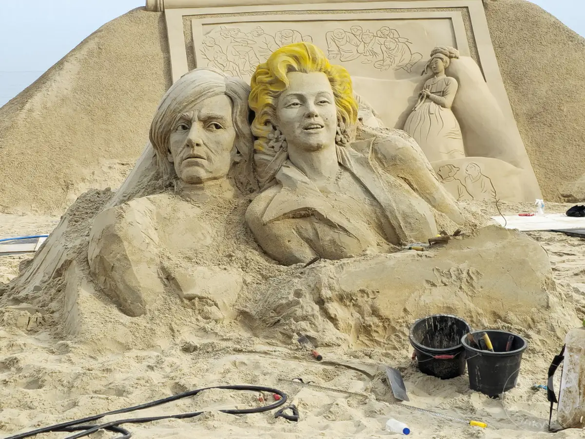 Eine beeindruckende Sandskulptur am Haeundae Beach in Busan, Südkorea, stellt ikonische Persönlichkeiten dar. Die detaillierte Ausführung und die imposante Größe der Figuren fangen die Aufmerksamkeit der Betrachter. Die Szenerie strahlt eine kreative und festliche Atmosphäre aus, die Besucher aus aller Welt anzieht.
