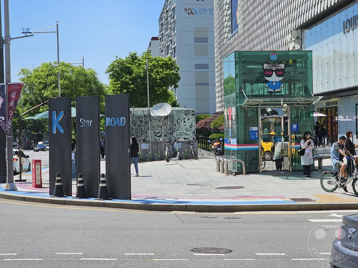 Südkorea, Seoul. Die K-Star Road in Gangnam, Südkorea, ist eine belebte Straße, die für ihre Verbindung zur K-Pop-Kultur und luxuriösen Einkaufsmöglichkeiten bekannt ist. Die sonnige Atmosphäre fängt die dynamische Energie der Stadt ein, während Fußgänger und Radfahrer die Gegend erkunden und durch die bunten Kunstinstallationen schlendern. Ein ikonischer Ort, der das pulsierende Herz des südkoreanischen Unterhaltungs- und Modeviertels widerspiegelt.