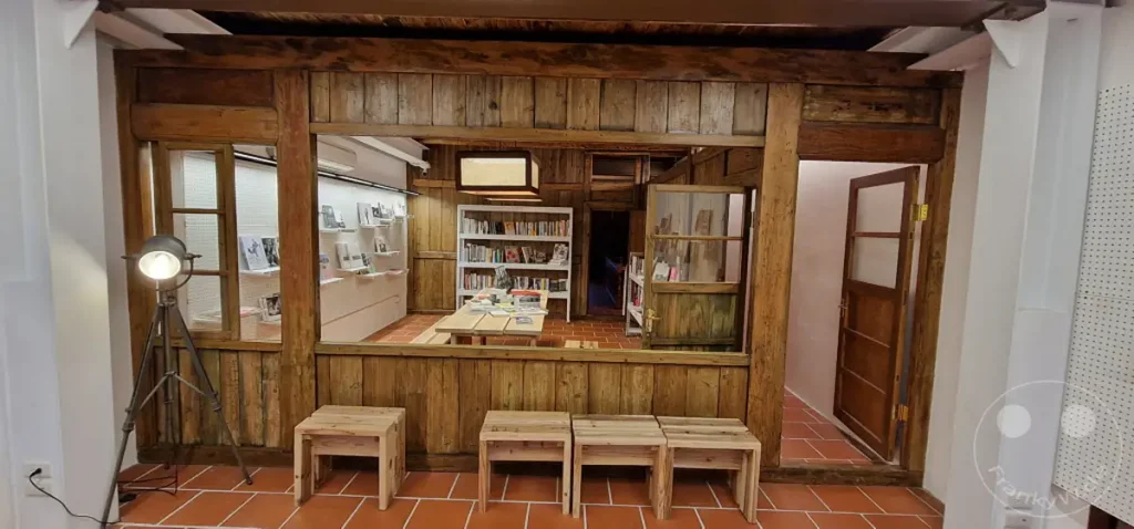 Ein rustikales Interieur mit Holzelementen und Terrakottafliesen in Taipeh, Taiwan, beherbergt einen charmanteren Buchladen. Antike Möbelstücke und ein Kronleuchter schaffen eine einladende und nostalgische Atmosphäre, die zum Verweilen und Entdecken einlädt.