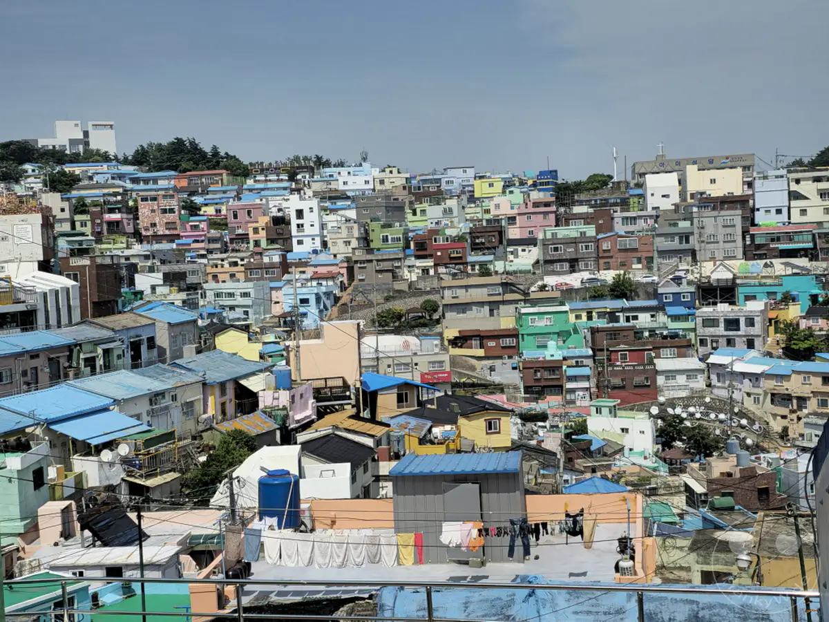 Das farbenfrohe Culture Village Gamcheon in Busan, Südkorea, schmiegt sich an einen steilen Hang und bietet einen atemberaubenden Blick auf die Küste. Zahlreiche bunte Häuser mit unregelmäßig angeordneten Dächern und engen Gassen prägen das Stadtbild und erzeugen eine lebendige, quirlige Atmosphäre. Die Architektur spiegelt die Geschichte und den Geist der Gemeinschaft dieses einzigartigen Ortes wider.