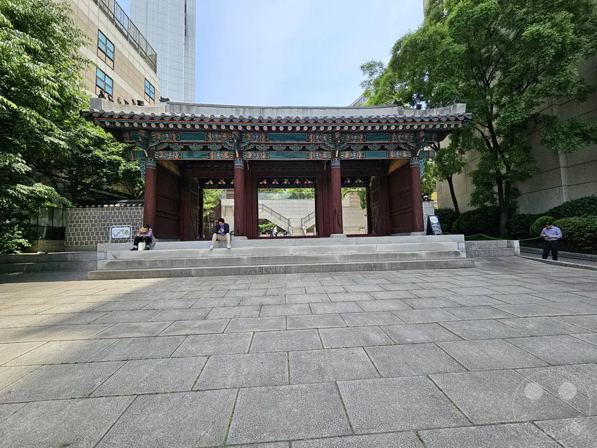 Im Herzen von Seoul, Südkorea, thront der Hwangudan Shrine, ein architektonisches Juwel, das die reiche Geschichte und Kultur des Landes widerspiegelt. Die traditionelle Architektur, geschmückt mit lebendigen Farben und kunstvollen Details, bildet einen faszinierenden Kontrast zur modernen Stadtlandschaft im Hintergrund. Eine friedliche Atmosphäre herrscht, während Besucher und Einheimische auf den breiten Steinstufen verweilen und die historische Bedeutung dieses Ortes auf sich wirken lassen.