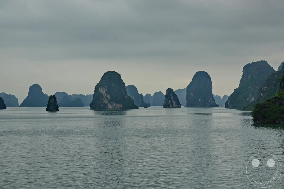 Die majestätische Ha Long Bucht in Vietnam offenbart eine atemberaubende Landschaft mit zahlreichen Karstfelsen, die aus dem ruhigen Meer emporragen. Die dichte Bewaldung auf den Inseln und die grauen, wolkenverhangenen Himmel erzeugen eine mystische und friedliche Atmosphäre. Dieses UNESCO-Weltkulturerbe lädt zu einer unvergesslichen Erkundung der natürlichen Schönheit Vietnams ein.