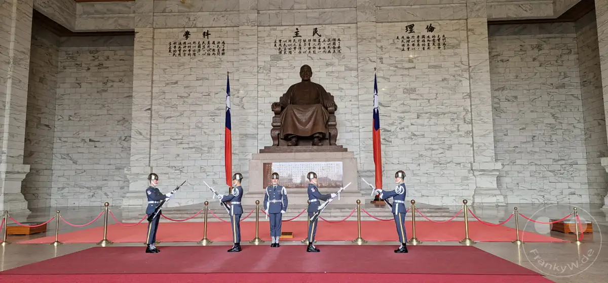 Soldaten in Uniformen führen eine Wachablösungszeremonie vor der Chiang Kai-shek Memorial Hall in Taipeh, Taiwan, durch. Die ernste Haltung der Wachsoldaten und die imposante Architektur der Gedenkstätte erzeugen eine würdevolle und respektvolle Atmosphäre. Die Szene fängt die Disziplin und denIONALen Stolz ein, der mit solchen Zeremonien verbunden ist.