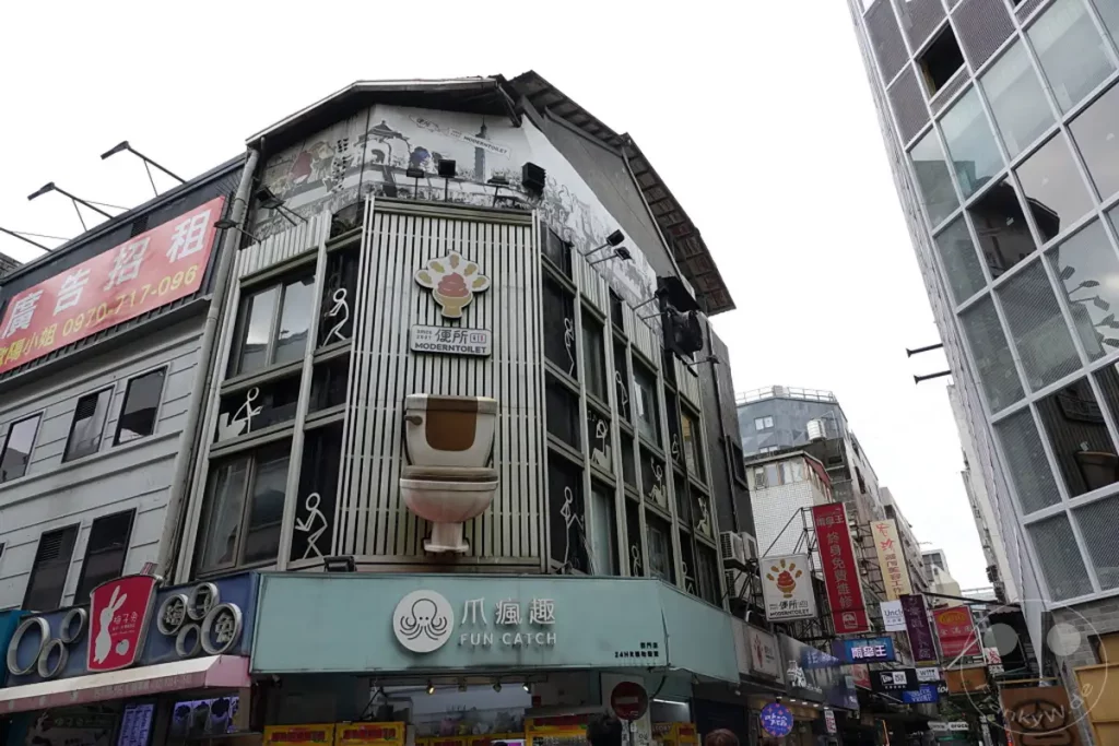 Die faszinierende Fassade eines "ModernToilet"-Geschäfts in Taipeh, Taiwan, fällt durch die ungewöhnliche Dekoration mit Toilettenschüsseln und humorvollen Piktogrammen ins Auge. Die bunten Werbeplakate und die detailreiche Architektur der umliegenden Gebäude schaffen eine lebendige und einzigartige Atmosphäre in der belebten Stadt. Ein Blick auf eine außergewöhnliche Ladenfront, die sicherlich die Aufmerksamkeit von Passanten auf sich zieht.
