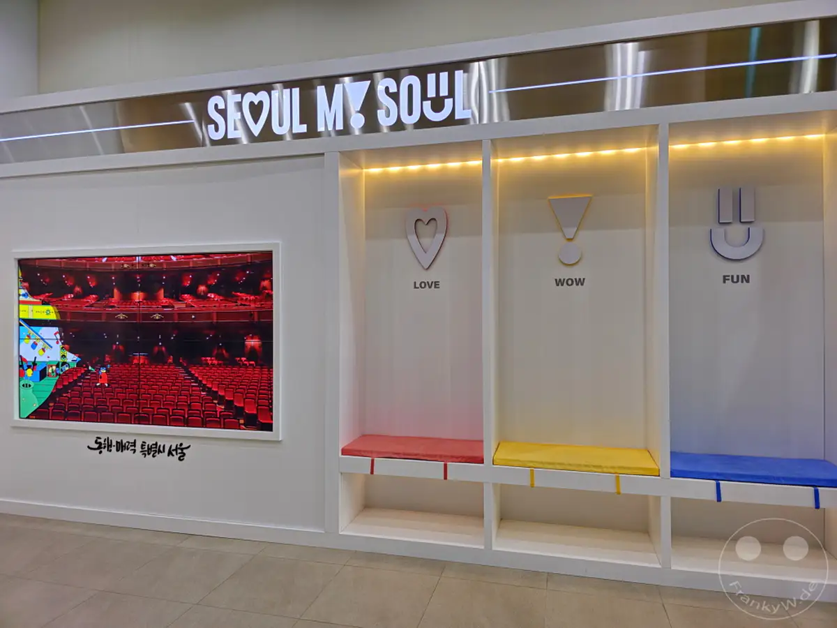 Die Ausstellung "Seoul My Soul" im Sejong Center for the Performing Arts in Seoul, Südkorea, präsentiert eine interaktive Installation mit symbolischen Darstellungen für Liebe, Staunen und Spaß. Helle Farben und ein modernes Design schaffen eine einladende und positive Atmosphäre für Besucher. Der Bildschirm im Hintergrund zeigt die leeren roten Sitze eines Theaters, die die Bühne für kulturelle Erlebnisse in Seoul andeuten.