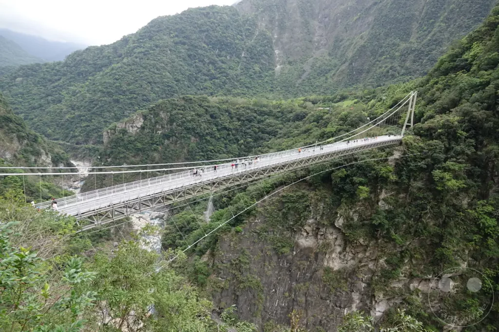 Die imposante Buluowan Suspension Bridge überspannt eine tiefe Schlucht im Taroko Nationalpark auf Taiwan. Umgeben von üppig grünen, steilen Berghängen und dem tosenden Flussbett darunter, vermittelt die Hängebrücke ein Gefühl von Abenteuer und Ehrfurcht vor der gewaltigen Naturkulisse. Besucher spazieren über die Brücke und genießen den atemberaubenden Ausblick auf die zerklüftete Landschaft und die natürliche Schönheit Taiwans.