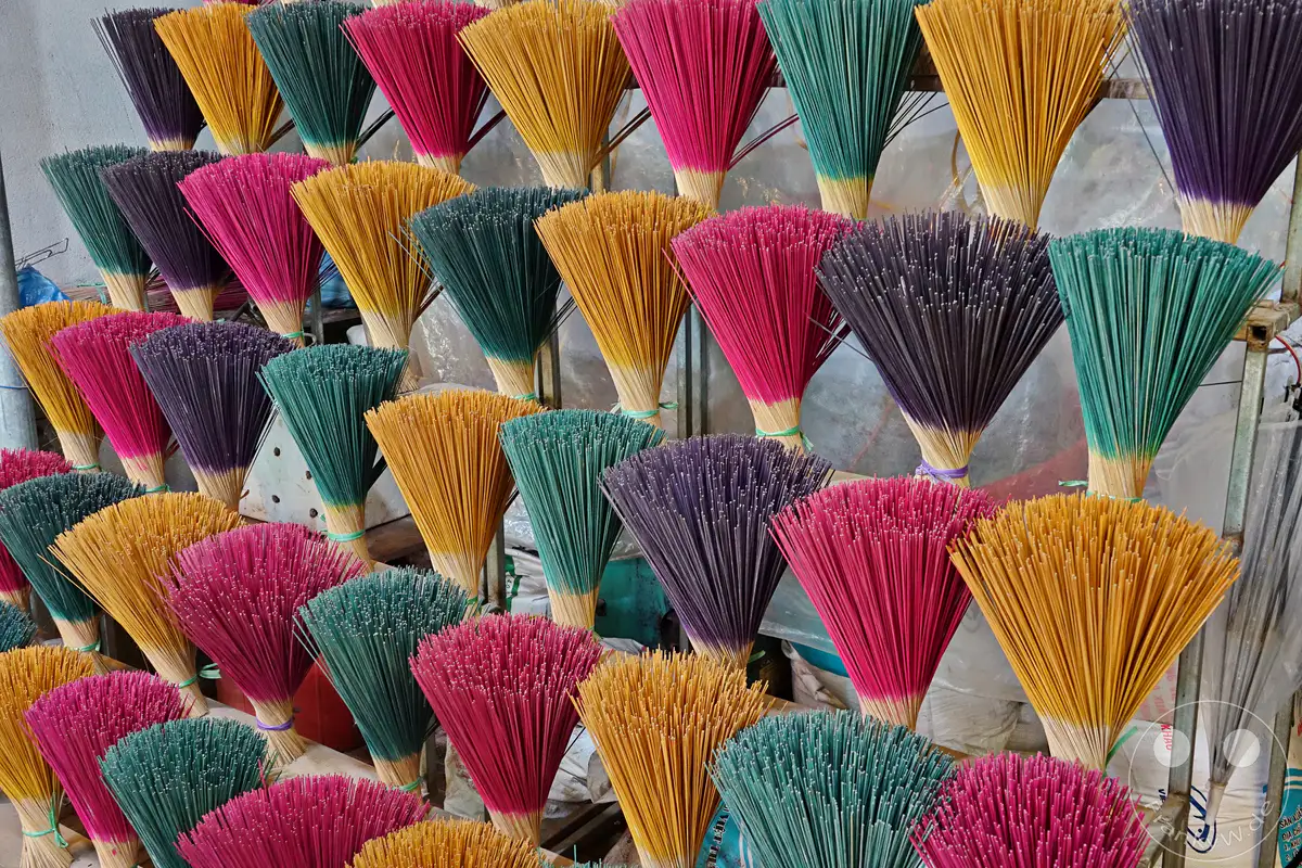 In Vietnam, in der Nähe von Hue, werden farbenfrohe Räucherstäbchen von Hand hergestellt. Die Bündel in leuchtenden Farben wie Pink, Gelb, Violett und Grün sind aufgereiht und warten auf die Weiterverarbeitung. Eine traditionelle Handwerkskunst, die sichtbar wird.