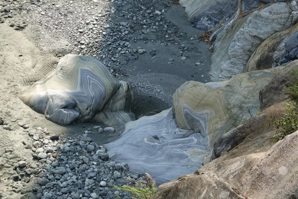 Das Bild zeigt eine detaillierte Aufnahme von Flussbettformationen im Taroko National Park auf Taiwan. Die geschwungenen Linien und die unterschiedlichen Gesteinsschichten im Yuewangting-Bereich zeugen von jahrelanger Erosion und geologischer Aktivität. Die Szenerie strahlt eine natürliche Ruhe und Erhabenheit aus, die die Kräfte der Natur eindrucksvoll darstellt.