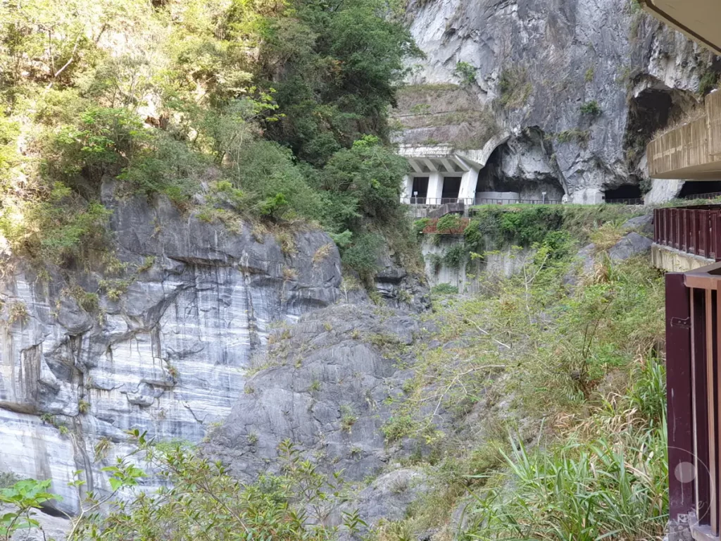 Der Tunnel of Nine Turns im Taroko Nationalpark in Taiwan offenbart die beeindruckende Schönheit der Marmorschlucht. Steile Felswände und Vegetation säumen den Weg durch dieses Naturwunder. Die Szenerie strahlt eine faszinierende Mischung aus natürlicher Erhabenheit und menschlicher Ingenieurskunst aus.