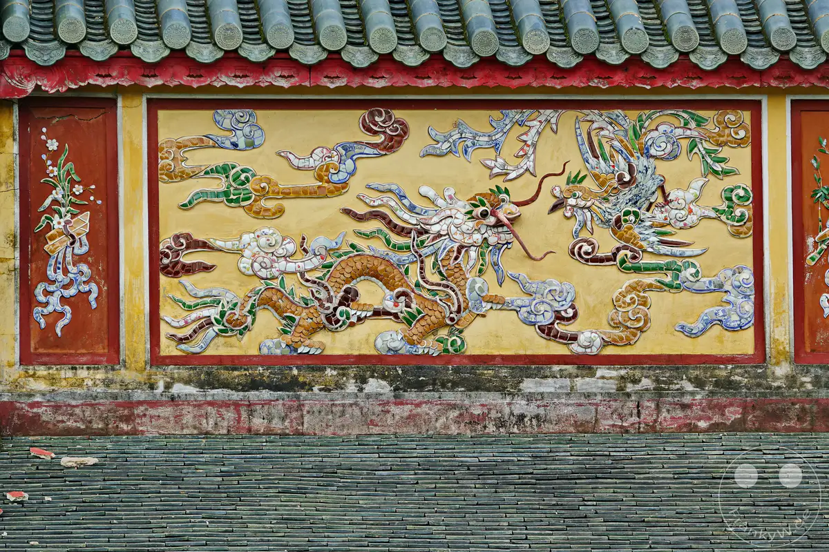 Die prunkvollen Drachenmotive der Imperial City in Hue, Vietnam, zieren die Fassade eines historischen Gebäudes. Diese detaillierten Keramikreliefs auf dem Gelände der Zitadelle strahlen eine Aura von Geschichte und kulturellem Reichtum aus. Das Motiv verkörpert die traditionelle ostasiatische Kunst und die architektonische Pracht des Kaiserpalastes.
