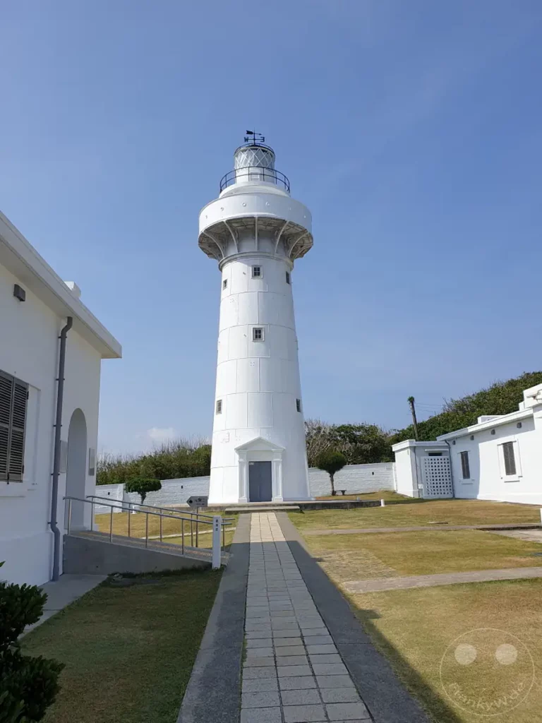 Der Eluanbi Lighthouse steht majestätisch unter einem klaren, blauen Himmel auf der südlichsten Spitze Taiwans. Die weiße Struktur erhebt sich imposant über eine gepflegte Grünfläche, umgeben von weiterer weißer Architektur und üppiger Vegetation. Die Szene strahlt eine ruhige und friedliche Atmosphäre aus, die die Schönheit der Küstenlandschaft hervorhebt.