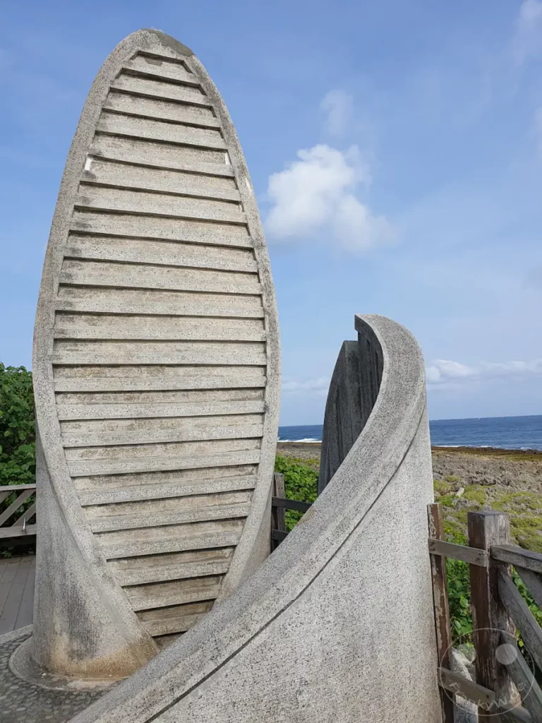 Das markante, spiralförmige Steindenkmal befindet sich am südlichsten Punkt Taiwans, nahe Eluanbi. Es erhebt sich vor der malerischen Küstenlandschaft mit dem blauen Meer und dem Himmel im Hintergrund. Die Architektur des Denkmals und die natürliche Umgebung erzeugen eine friedliche und beeindruckende Atmosphäre.