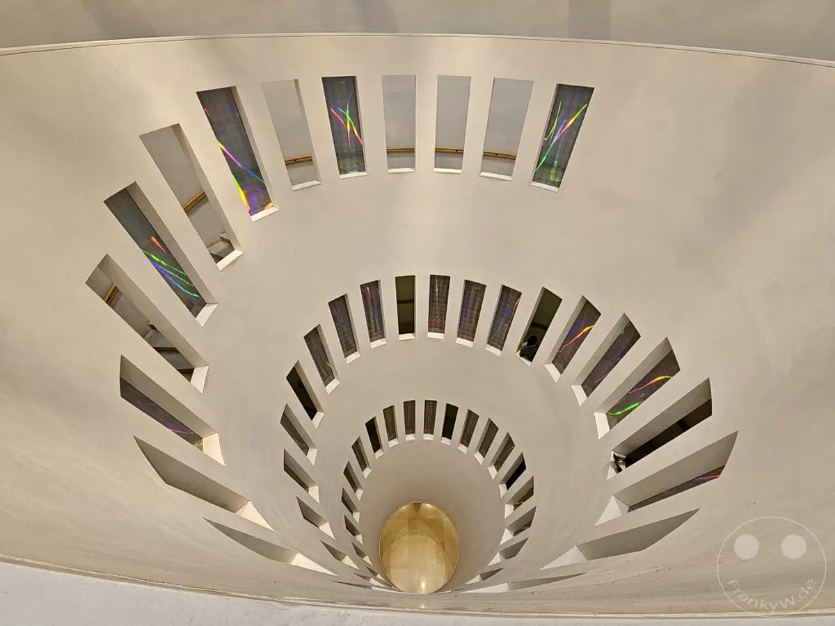 Eine spiralförmige Treppenarchitektur im Leeum Museum of Art in Seoul, Südkorea, wird durch Lichteinfälle durch schmale Fenster illuminiert. Die bunten Reflexionen erzeugen ein faszinierendes Muster auf den weißen Wänden des Innenraums. Die Szene vermittelt ein Gefühl von Weite und künstlerischer Gestaltung, das zum Entdecken einlädt.