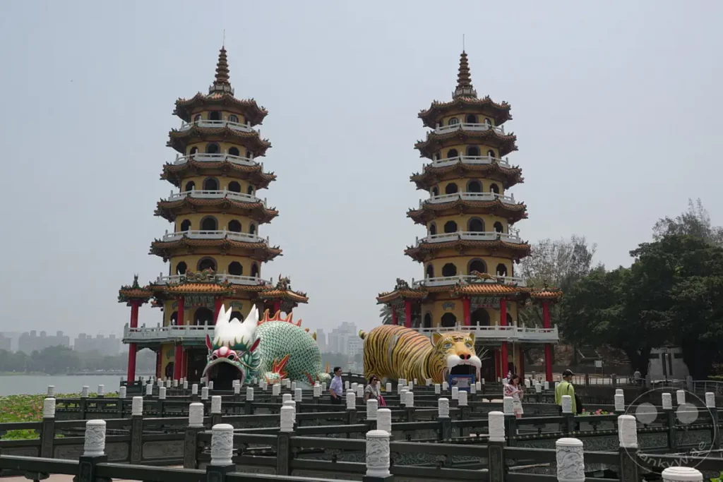 Die zwei malerischen Pagoden des Drachen- und Tiger-Tempels in Zuoying, Taiwan, erheben sich majestätisch über dem Lotussee. Vor ihnen stehen beeindruckende Skulpturen eines Drachen und eines Tigers, die den Eingang zur Anlage markieren. Die Szenerie strahlt eine ruhige und zugleich beeindruckende Atmosphäre aus, die Besucher aus aller Welt anzieht.