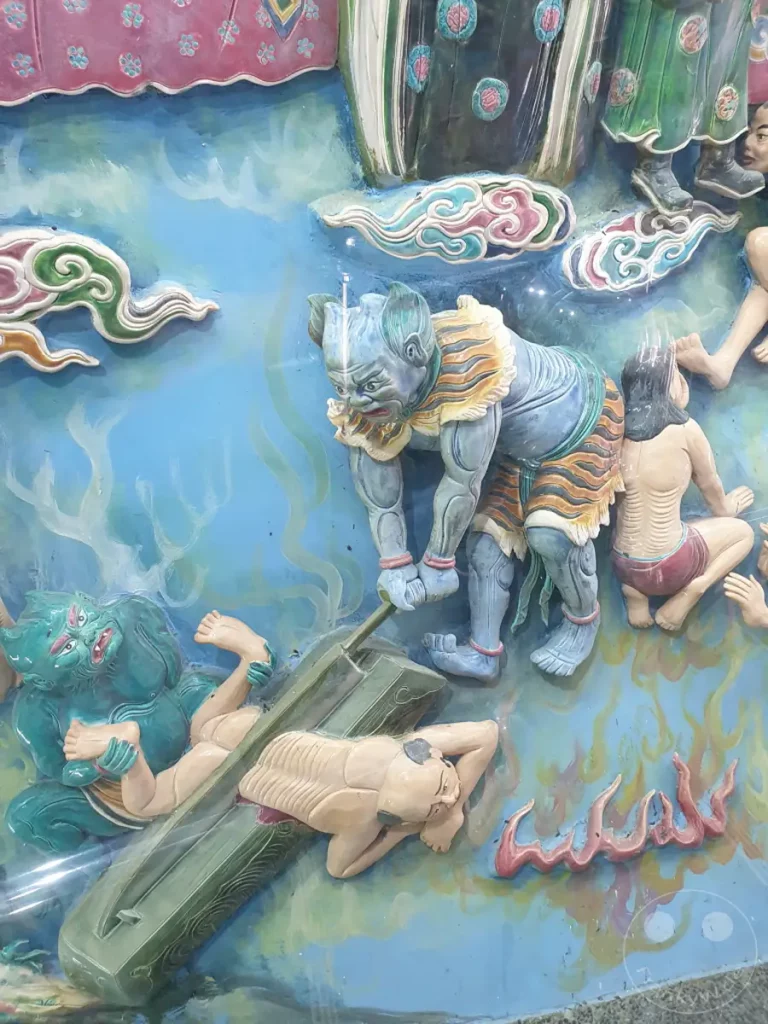 Eine detaillierte Keramikrelief-Darstellung aus Taiwan zeigt eine Szene, die an die buddhistische Hölle erinnert, mit mythischen Kreaturen und leidenden Seelen. Die lebendigen Farben und die dynamische Komposition vermitteln eine düstere und zugleich faszinierende Atmosphäre, die in einem Tempel in Zuoying zu finden ist. Die kunstvollen Figuren, darunter ein Tiger-ähnliches Wesen, scheinen in einem dramatischen Moment gefangen zu sein.
