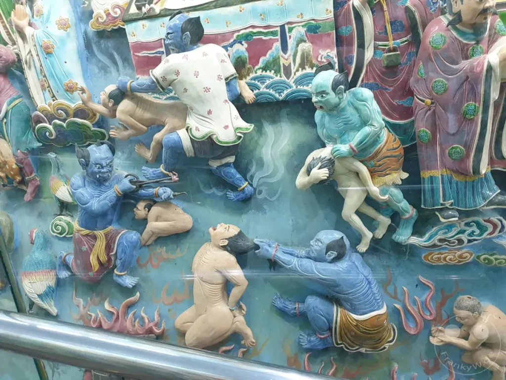 Ein kunstvolles Relief stellt Szenen aus der chinesischen Mythologie und dem Buddhismus dar, darunter die Hölle und mythologische Figuren. Die lebendigen Farben und die detaillierte Ausführung vermitteln eine dramatische und kraftvolle Atmosphäre. Dieses Kunstwerk ist Teil einer größeren Tempelanlage in Zuoying, Taiwan.