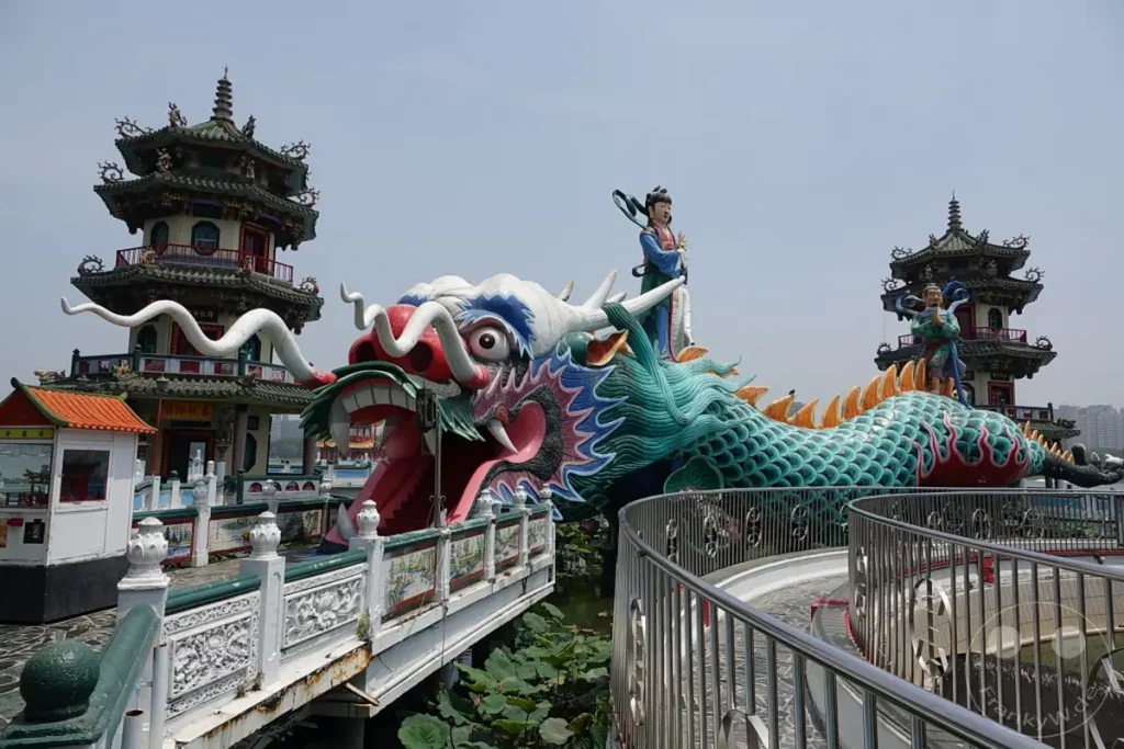 Die Drachen- und Tigertore der Spring and Autumn Pavilions in Zuoying, Taiwan, sind ein beeindruckendes Wahrzeichen. In der Mitte des Bildes dominiert die farbenprächtige Drachenstatue mit geöffnetem Maul, über die Besucher schreiten können. Im Hintergrund erheben sich traditionelle chinesische Pagoden, die eine spirituelle Atmosphäre vermitteln.