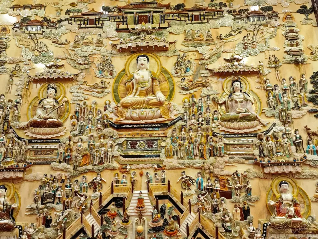 Eine beeindruckende Wandreliefkunst im Fo Guang Shan Buddha Museum in Kaohsiung, Taiwan, zeigt zahlreiche fein gearbeitete Statuen von Buddha-Figuren und Bodhisattvas, die in detaillierten Szenen angeordnet sind. Die Szenerie strahlt eine tiefe spirituelle Ruhe und historische Bedeutung aus, eingebettet in die architektonische Pracht des Museums. Dieses Kunstwerk bietet einen faszinierenden Einblick in die buddhistische Tradition und Kunstfertigkeit.
