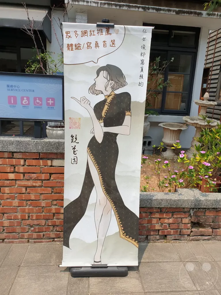 Ein aufgerolltes Banner mit einer Modeillustration im chinesischen Stil steht vor einem Gebäude in Tainan, Taiwan. Das Banner wirbt für eine Empfehlung von Influencern und ist Teil des Blueprint Culture & Creative Park. Die Illustration einer elegant gekleideten Frau vermittelt ein Gefühl von Stil und kulturellem Erbe.
