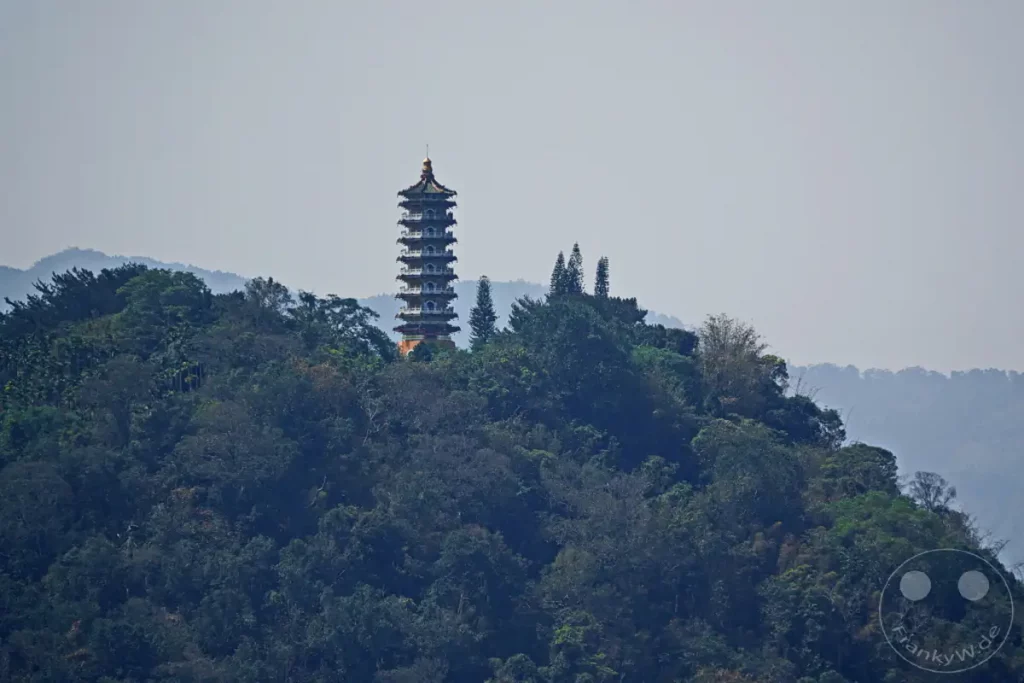 Die Ci'en Pagoda thront majestätisch auf einem bewaldeten Berg über dem Sun Moon Lake in Taiwan. Der Himmel ist leicht diesig und verleiht der Szene eine friedliche und leicht mystische Atmosphäre. Die üppige Vegetation und die entfernten Hügel spiegeln die natürliche Schönheit der Region wider.