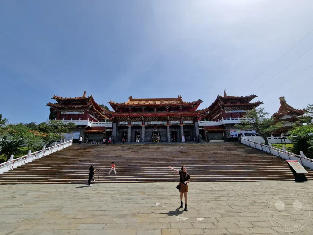 Der imposante Wenwu Tempel am Sun Moon Lake in Taiwan thront majestätisch über einer breiten Steintreppe. Die traditionelle chinesische Architektur mit ihren roten Dächern und verzierten Fassaden bildet einen atemberaubenden Anblick vor dem klaren blauen Himmel. Touristen und Einheimische bevölkern die weitläufige Anlage und genießen die friedliche Atmosphäre und die beeindruckende Aussicht.