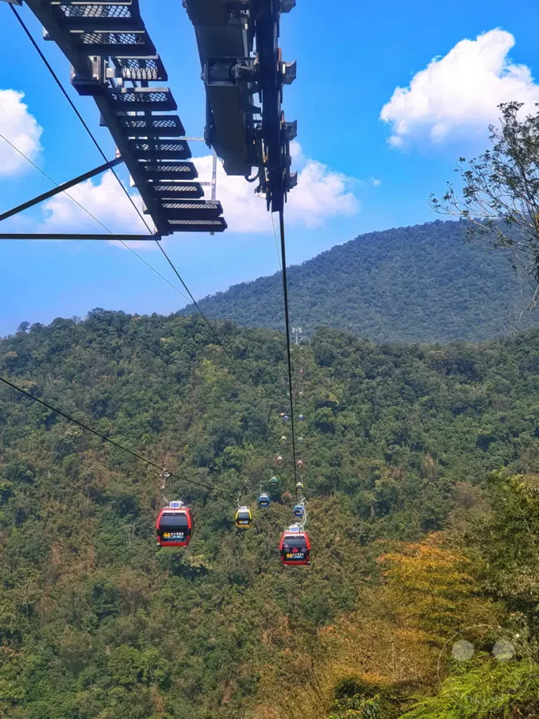 Die Riyuetanlan Seilbahnstation überblickt die üppige Berglandschaft rund um den Sun Moon Lake in Taiwan. Mehrere bunte Gondeln bewegen sich auf einer langen Seillinie über das grüne Tal und bieten atemberaubende Ausblicke. Die Szene vermittelt ein Gefühl von Abenteuer und Erhabenheit inmitten der natürlichen Schönheit Taiwans.