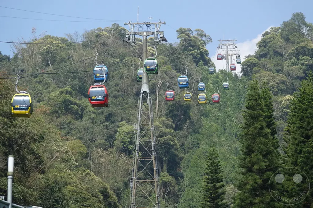 Mehrere bunte Gondeln der Riyuetanlan Ropeway Station ziehen über den üppig bewachsenen Sun Moon Lake in Taiwan. Die Seilbahn überwindet die hügelige Berglandschaft und bietet atemberaubende Ausblicke auf die Natur. Die Szene vermittelt ein Gefühl von Abenteuer und Erhabenheit inmitten der grünen Weiten.