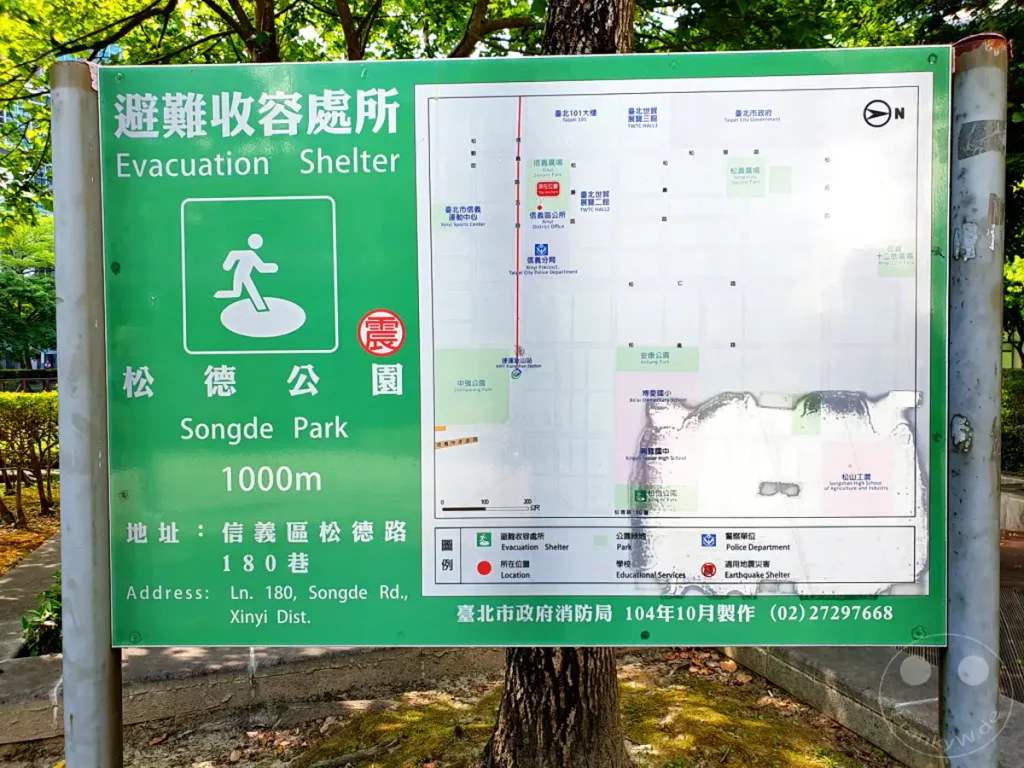 Ein Straßenschild in Taipeh, Taiwan, informiert über einen Evakuierungs-Shelter im Songde Park. Auf dem Schild ist eine Karte mit verschiedenen Orten und Einrichtungen in der Nähe abgebildet. Die informative Aufmachung vermittelt ein Gefühl von Sicherheit und lokaler Vorbereitung auf Notfälle.