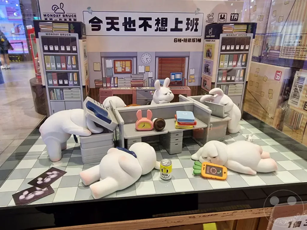 In Taipeh, Taiwan, im Guang Hua Digital Plaza, werden die humorvollen "Monday Bruce" Figuren präsentiert, die das Bürochaos und die Müdigkeit des Arbeitsalltags auf liebevolle Weise darstellen. Die Szene mit den schlafenden und träumenden Plüschhasen fängt eine entspannte, fast schon resignierte Stimmung ein, die durch die vielen kleinen Details wie die Dosen und die Handys unterstrichen wird. Es handelt sich um eine charmante Vitrinenauslage, die den Charme von niedlichen Sammelfiguren für Liebhaber des Genres einfängt.