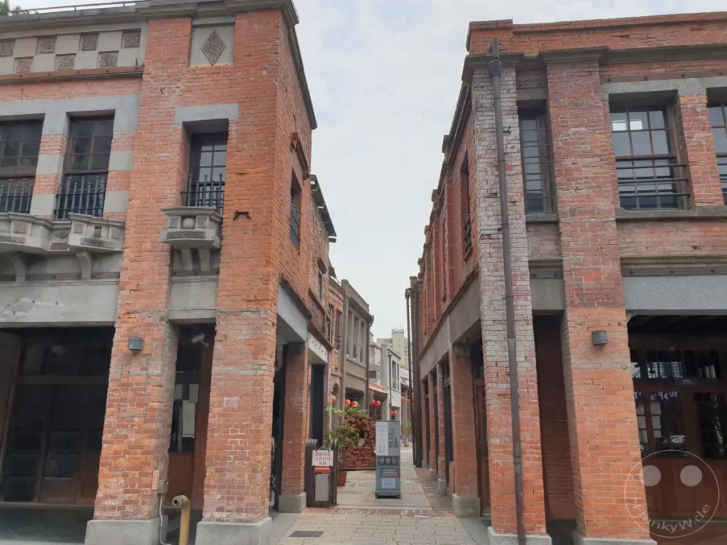 Alte Backsteingebäude säumen eine schmale Gasse im Bopiliao Historical Block in Taipeh, Taiwan. Die Architektur zeugt von vergangener Zeit und verleiht der Szene eine historische und leicht melancholische Atmosphäre. Das Zwielicht und die engen Gassen laden zum Erkunden ein.