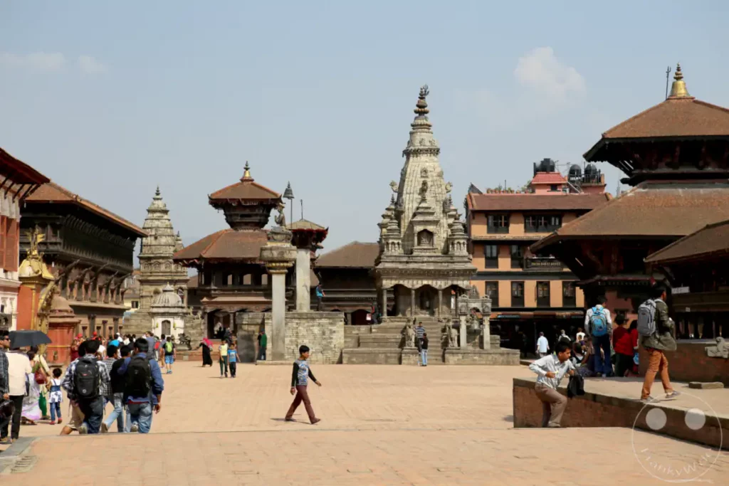 Der lebhafte Platz in Bhaktapur, Nepal, ist umgeben von traditioneller nepalesischer Architektur und Tempeln. Besucher und Einheimische beleben die historische Stätte und schaffen eine Atmosphäre kulturellen Austauschs.