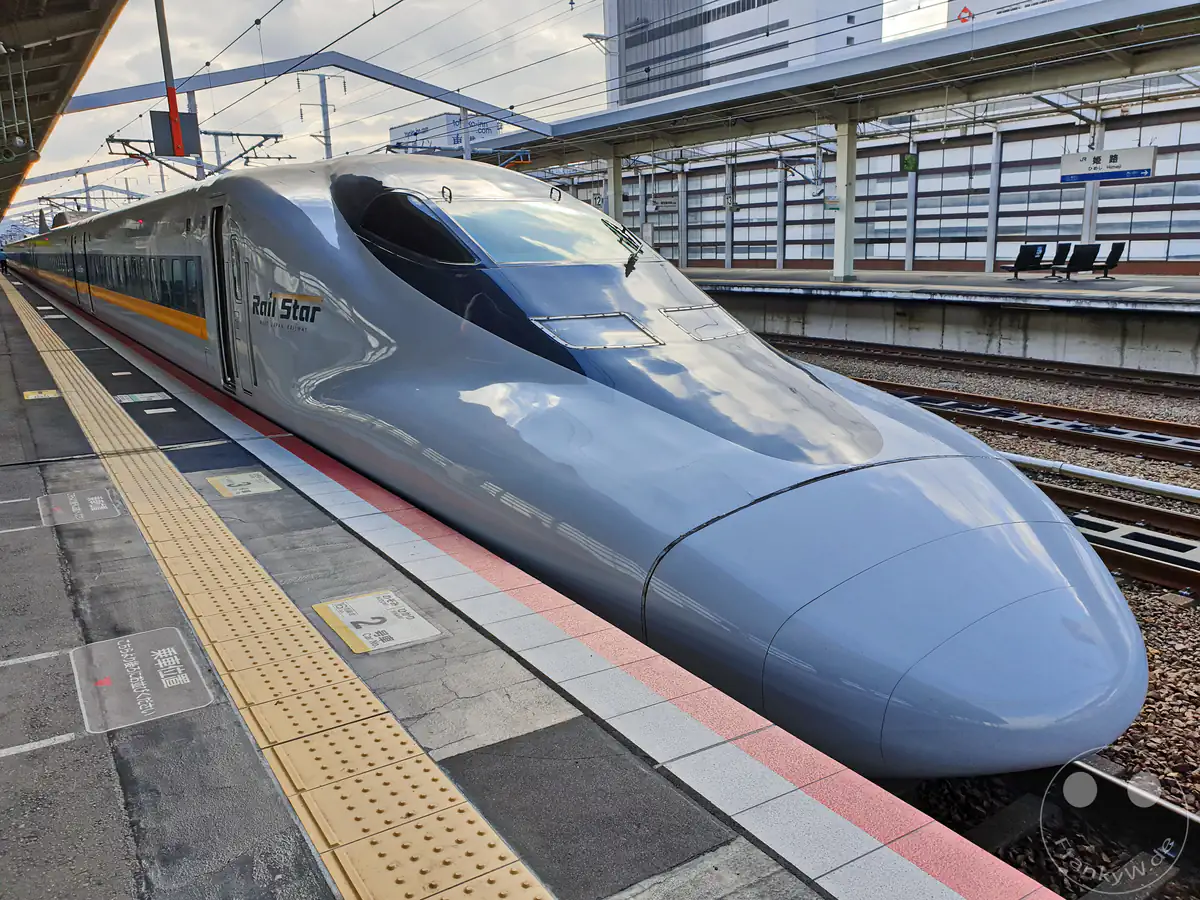 Ein aerodynamischer Shinkansen-Hochgeschwindigkeitszug der Baureihe 700 im „Hikari Rail Star“-Design steht einfahrbereit am Bahnsteig des japanischen Bahnhofs Himeji.