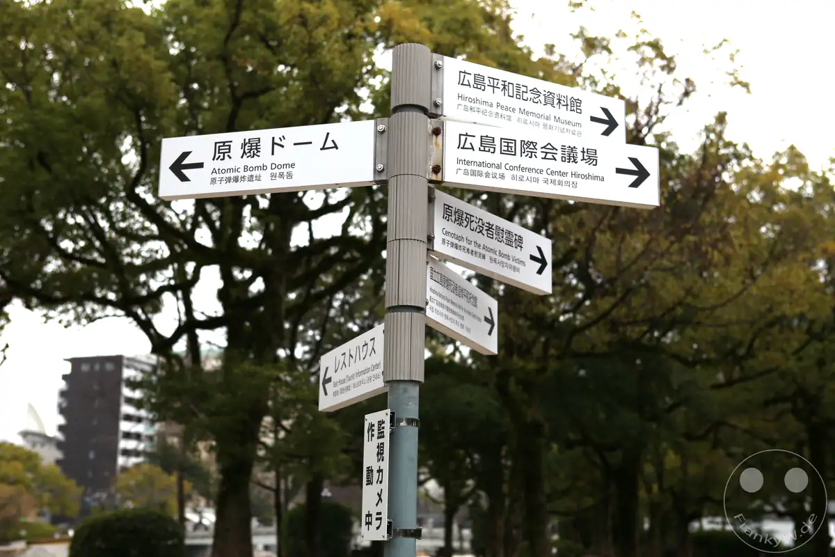 Wegweiser im Friedenspark Hiroshima zeigt Richtungen zum Atombombendom, dem Friedensmuseum und weiteren wichtigen Gedenkstätten für internationale Besucher auf Japanisch und Englisch.