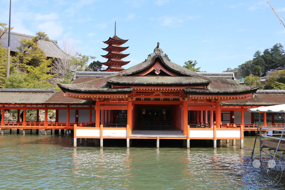 Die markante zinnoberrote Haraiden-Gebetshalle des Itsukushima-Schreins steht auf Pfählen im Meer, während im Hintergrund die fünfstöckige Gojunoto-Pagode emporragt.