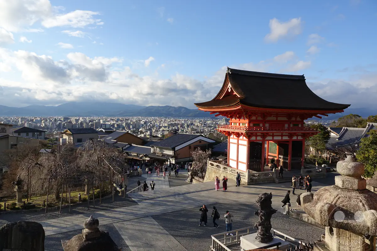 Das leuchtend rote Niomon-Tor des Kiyomizu-dera Tempels steht erhaben auf dem Tempelplatz in Kyoto und bietet Besuchern einen weiten Panoramablick über das historische Viertel und die flache Stadtlandschaft.
