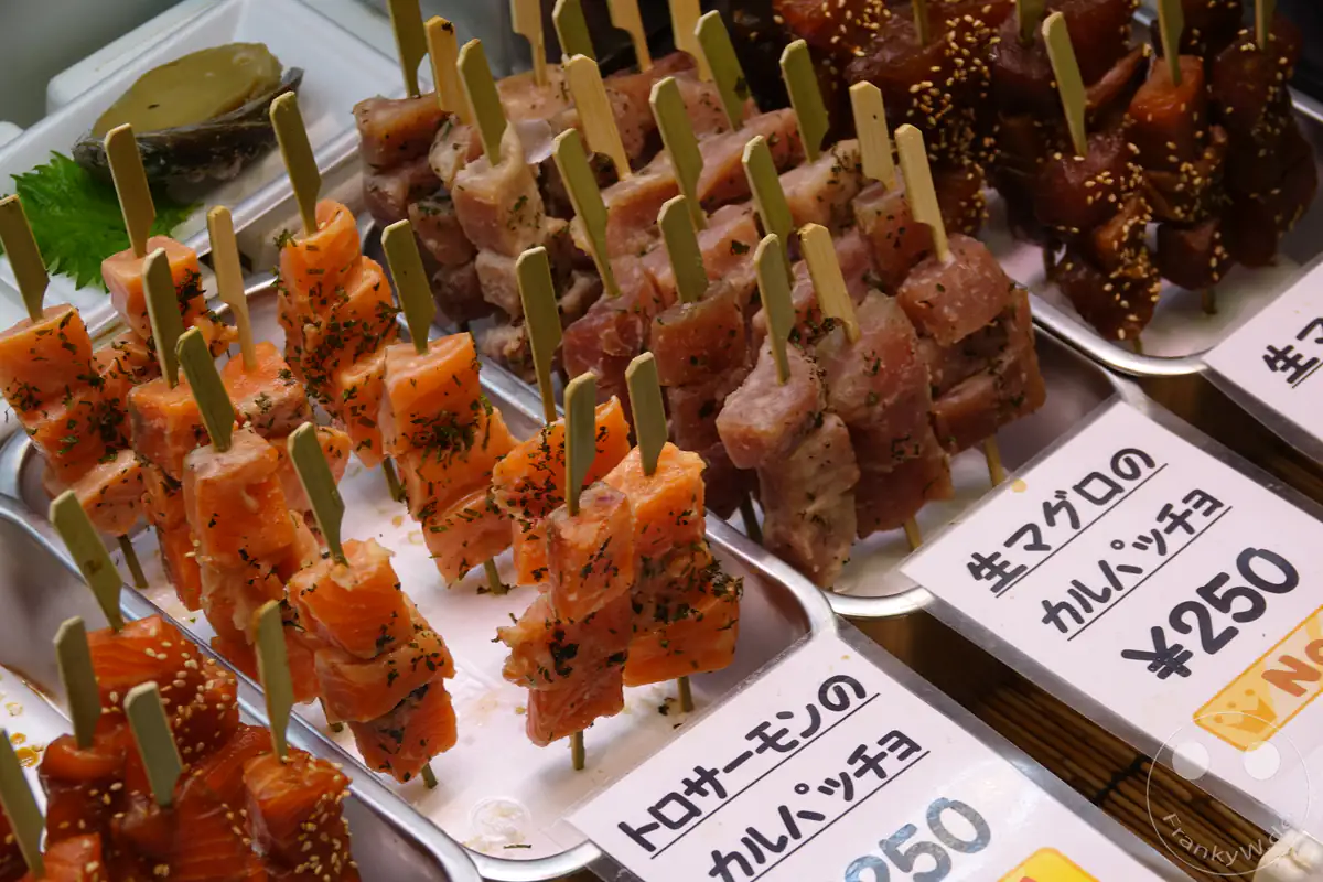 Frische Sashimi-Spieße aus Lachs und Thunfisch werden als mariniertes Carpaccio-Streetfood mit Preisschildern auf einem japanischen Fischmarkt in Kyoto zur Auswahl angeboten.