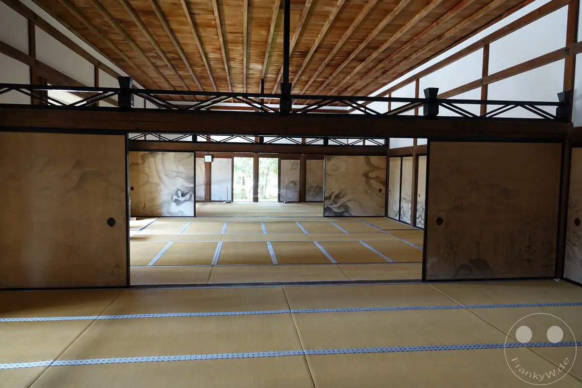 Ein Blick in das traditionelle Innere der Hojo-Halle des Ryoan-ji Tempels in Kyoto mit weitläufigen Tatami-Mattenböden und kunstvoll bemalten Fusuma-Schiebetüren unter einer hölzernen Deckenkonstruktion.