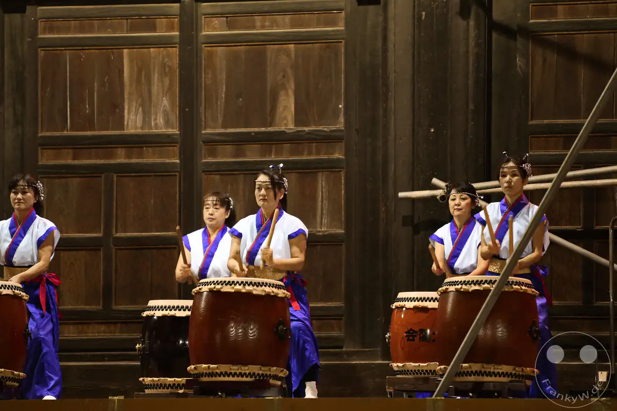Japanische Musikerinnen in traditionellen Gewändern spielen kraftvoll auf großen Taiko-Trommeln während des historischen Hadaka-Matsuri-Festivals am Saidai-ji Kannon-in Tempel in Okayama.