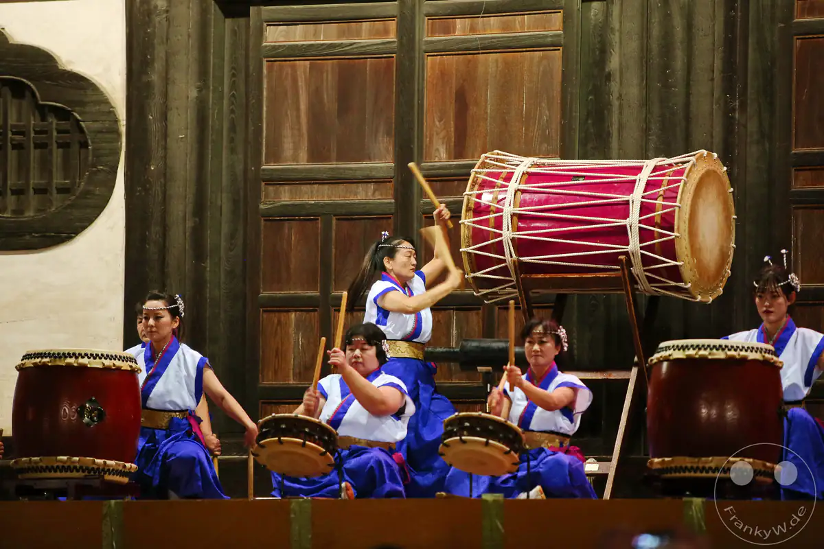 Eine japanische Musikerin holt schwungvoll mit den Bachi-Trommelstöcken aus, um eine große hängende Oke-daiko-Trommel während der rituellen Festivitäten am Saidai-ji Kannon-in Tempel in Okayama zu schlagen.